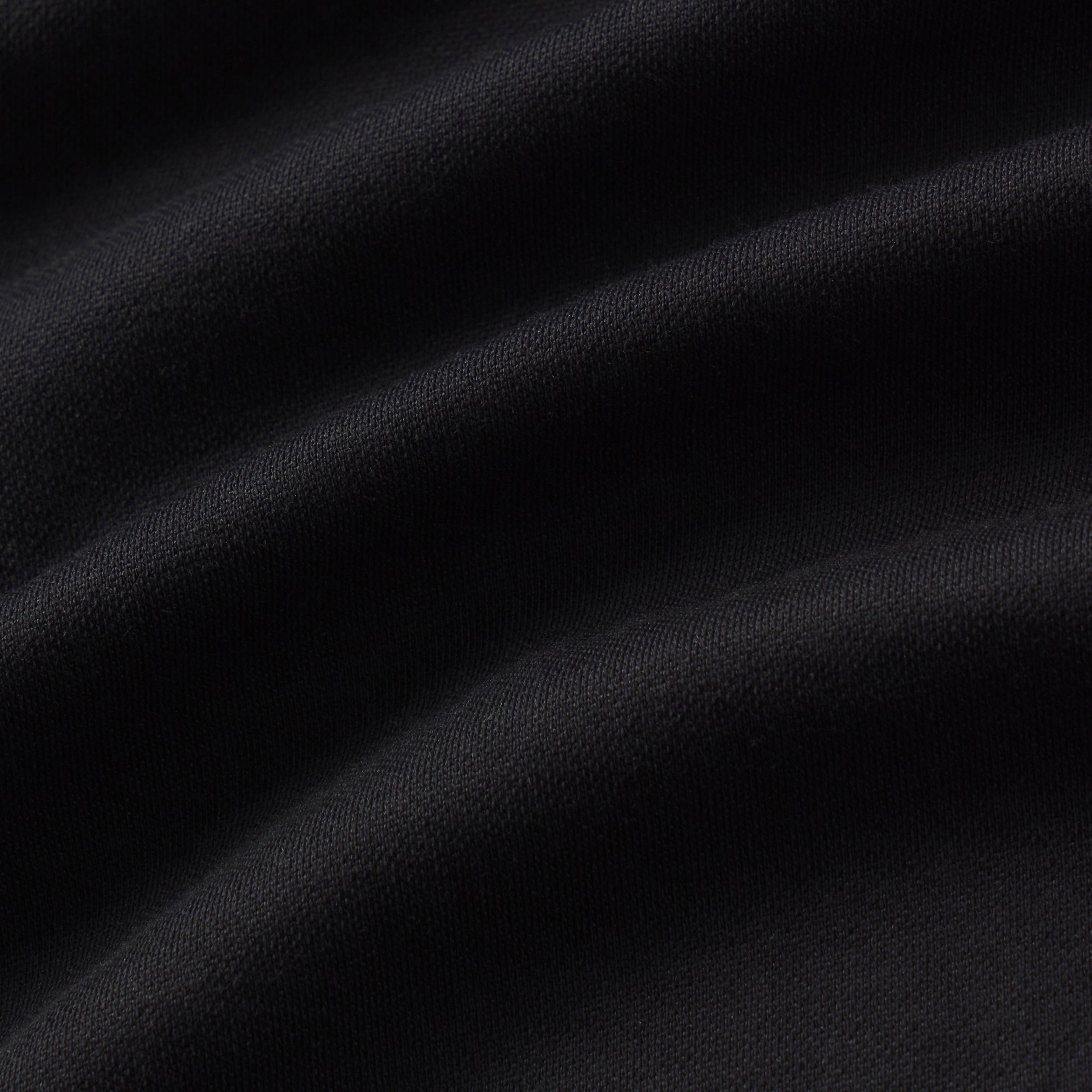 Close-up of black fabric texture, showcasing the smooth material used for the Tech Polo.