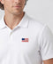 A man wearing the Clubhouse Pique Polo USA Flag in True White.