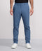 A person stands against a plain light background, shown from shoulders to feet, wearing Jack Archer’s Jetsetter Tech Pant in light blue (slim-fit, wrinkle-resistant), paired with a black shirt and white sneakers.