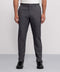 A person wears Jack Archer's Jetsetter Tech Pant in straight-fit charcoal gray, paired with a white tucked-in shirt and black shoes, standing against a plain light gray background. The image shows them cropped from the shoulders down.