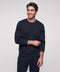A man in a midnight navy crewneck sweatshirt and matching sweatpants, hand on sleeve.
