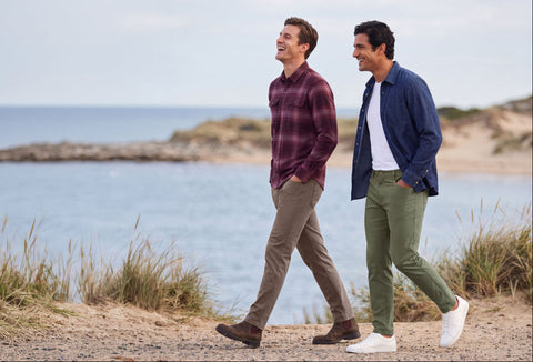 Two men in burgundy plaid and navy shirts walking a beach path in Charter Twill Pants, Deep Taupe and Olive