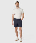 Man wearing Jetsetter Tech Short in navy blue, paired with a white t-shirt and white sneakers, standing against a neutral background.