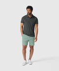 Man wearing Jetsetter Tech Short in mint green, paired with a dark polo shirt and white sneakers.