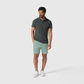 Man wearing Jetsetter Tech Short in mint green, paired with a dark polo shirt and white sneakers.