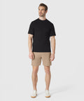 Man wearing Jetsetter Tech Short in beige, paired with a black t-shirt and white sneakers.