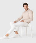 Man wearing Legacy Polo Sweater, sitting on a chair.