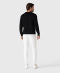 Man wearing black Legacy Polo Sweater and white pants, rear view.