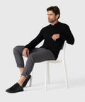 Legacy Polo Sweater in black, worn by a seated model, showcasing refined knitwear style.