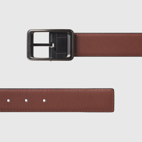 Reversible leather belt with metal buckle showcasing brown and black sides.