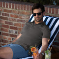 Man wearing a Jetsetter Tech Polo sitting outdoors with a drink.