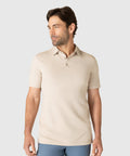 Man wearing a beige Tech Polo with a tailored cut and structured collar.