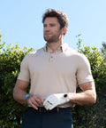Man wearing beige Tech Polo with tailored fit and structured collar outdoors.