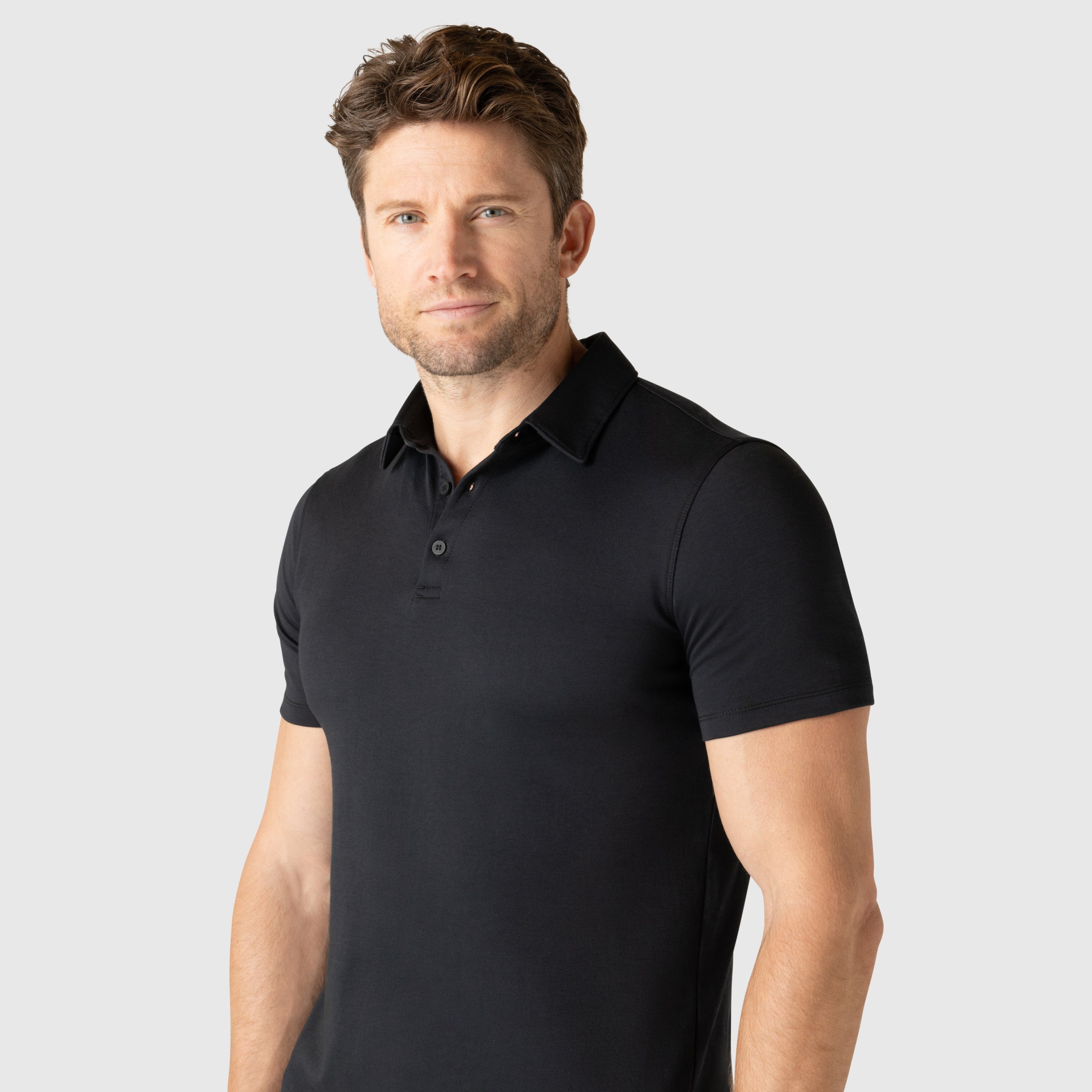 Man wearing a black Tech Polo with a tailored fit and structured collar.