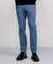 A person is shown from the waist down wearing Jetsetter Tech Pant Slim Fit in light blue and black dress shoes, standing against a plain, light background. The pants have a wrinkle-free finish and only the lower body is visible.