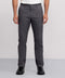 A person wearing Jetsetter Tech Pant Slim Fit in gray, paired with a white shirt and black sneakers, stands against a plain light gray background. The image displays the individual from shoulders to feet.