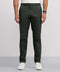 A person wears dark green Jack Archer Jetsetter Tech Pant—wrinkle-resistant and water-repellent—with a white shirt, black wristwatch, and white sneakers, standing against a plain light background; only the lower half is visible.