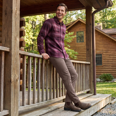 A man wearing Charter Twill Pant in Deep Taupe, sitting outdoors in a casual setting.