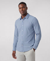 A man wearing the Everywear Shirt Shorter Length in Chambray Blue with a button-down collar.