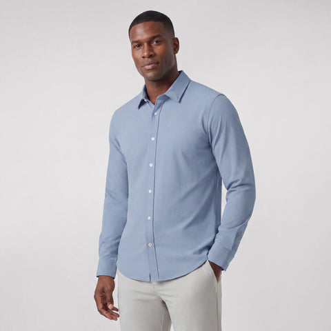 A man wearing the Everywear Shirt Shorter Length in Chambray Blue with a button-down collar.