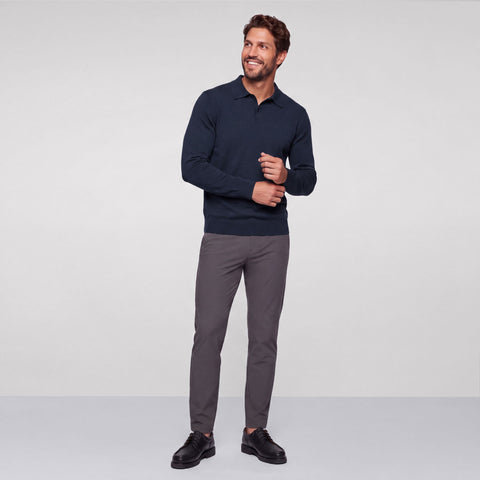 Full-length view of a navy knit long-sleeve polo with charcoal trousers and black derbies.