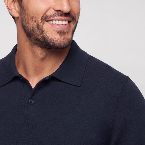 Close-up of a navy knit long-sleeve polo worn with the collar open.