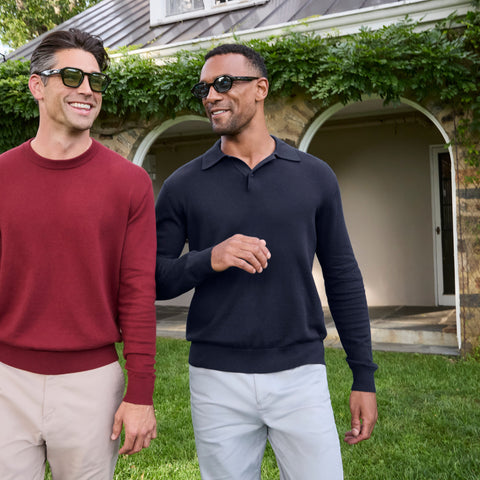 Two men outdoors on a lawn, one in a navy knit long-sleeve polo and one in a burgundy crewneck sweater.