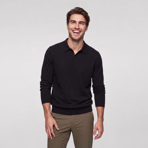 A black knit long-sleeve polo worn open at the collar with olive chinos.