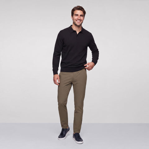 A black long-sleeve knit polo worn with olive chinos and navy sneakers.