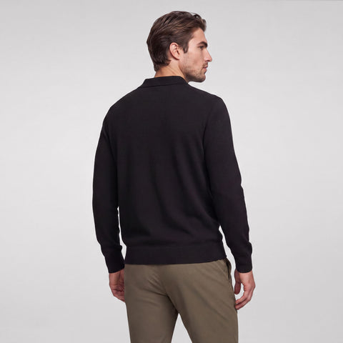 Back view of a black long-sleeve knit polo worn with olive chinos.