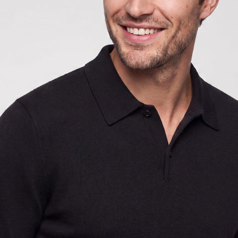 Close-up of a black knit long-sleeve polo worn with the collar open.