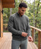 A man in a heather gray full-zip sweater on a wooden deck surrounded by trees.