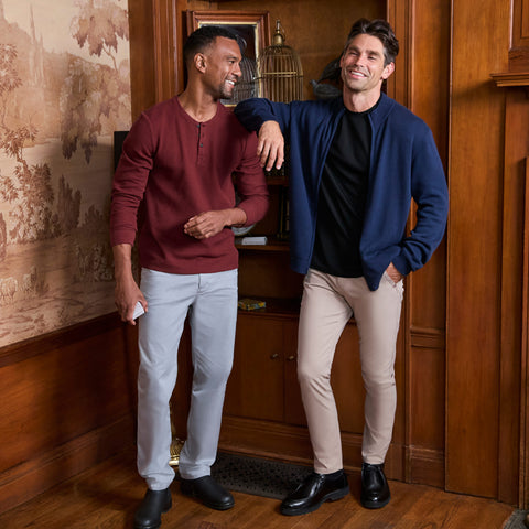 Two men in a wood-panelled room, one wearing a navy full-zip sweater over a black tee.