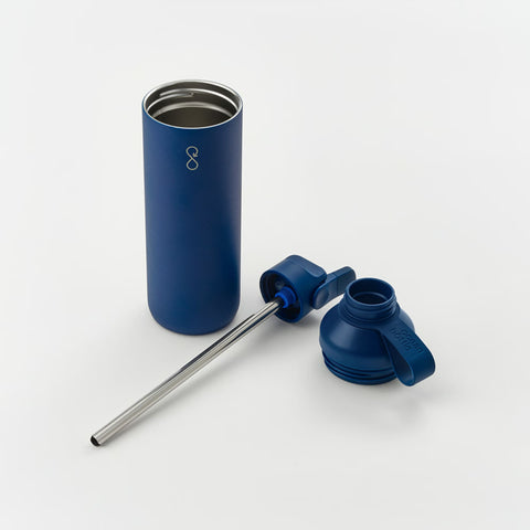 A navy insulated bottle standing open beside its straw lid and a stainless steel straw.