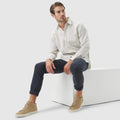 Man wearing deep blue pants and light shirt sitting on white block, showcasing Golf Game Essentials.